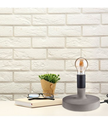 En bordlampe i beton der spreder et varmt og hyggeligt lys i stuen